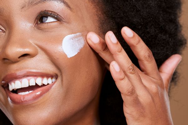 Woman smiling and applying cream to face