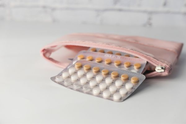 Birth control pill packets coming out of a pink toilet bag