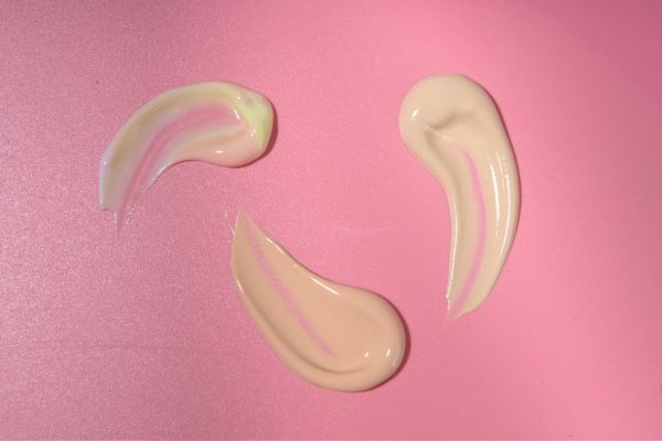 Concealer smeared three times on pink background