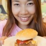 Woman smiling and holding up burger