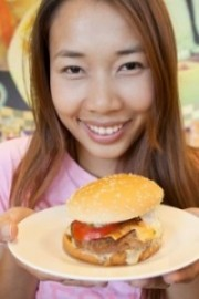 Woman smiling and holding up a burger