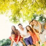 Group of friends smiling outside under a green tree