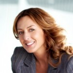 Woman in grey blazer, smiling at camera