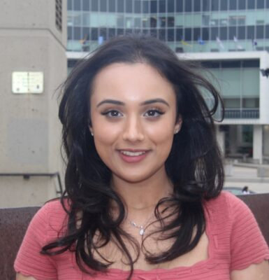 Mahek Shergill smiling outside in front of concrete buildings