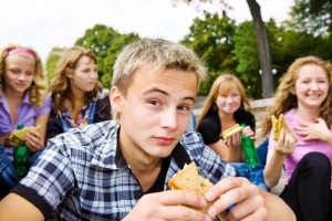 Pairs mangeant des sandwichs et assis dehors