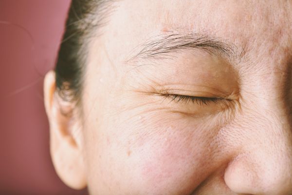 Up close image of woman scrunching face with eyes closed