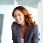 Femme en blazer gris, souriant à la caméra