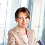 Femme en blazer beige, souriant à la caméra